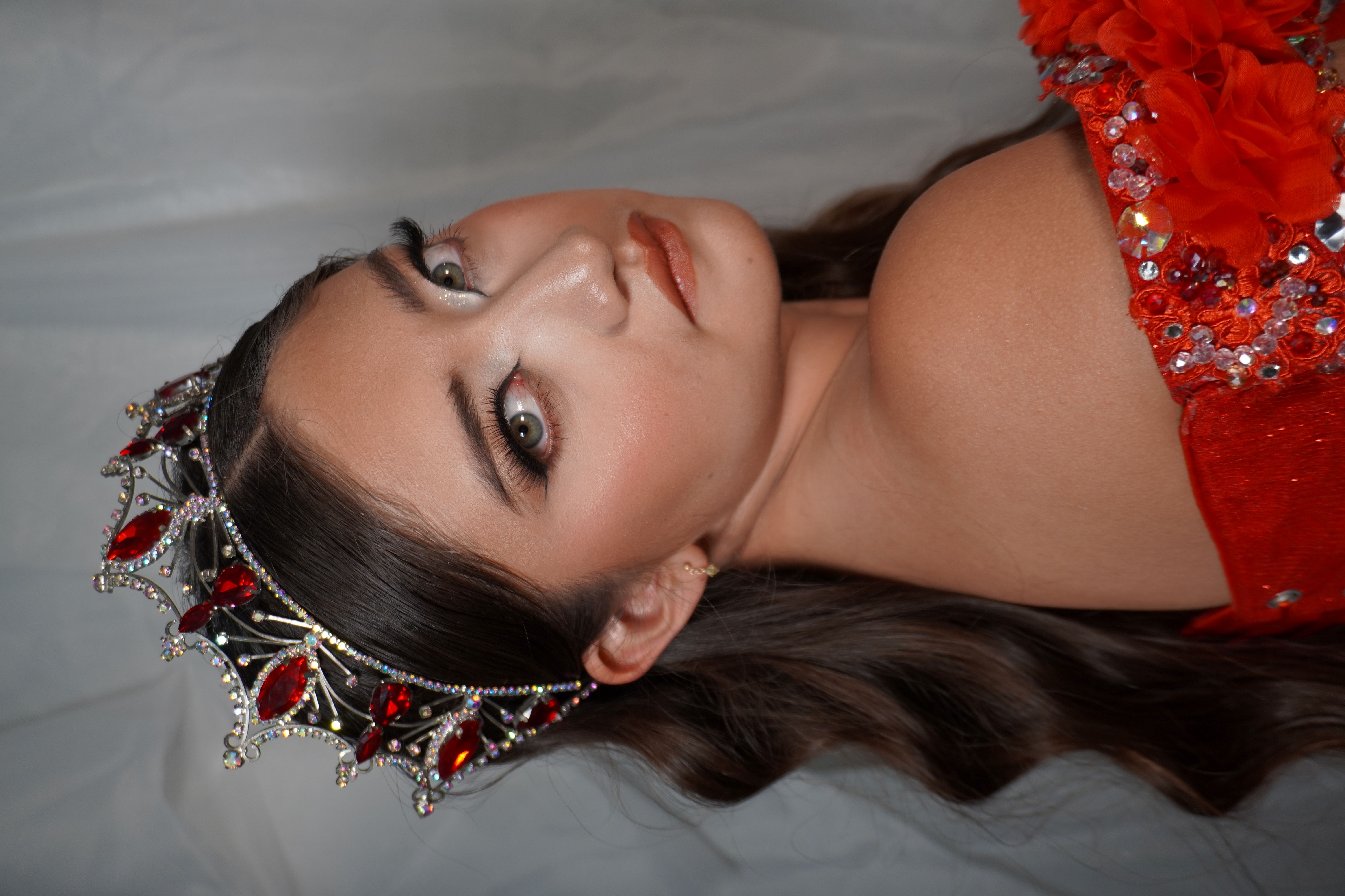 Quinceañera de rojo con maquillaje smoky intenso y corona de cristales rojos