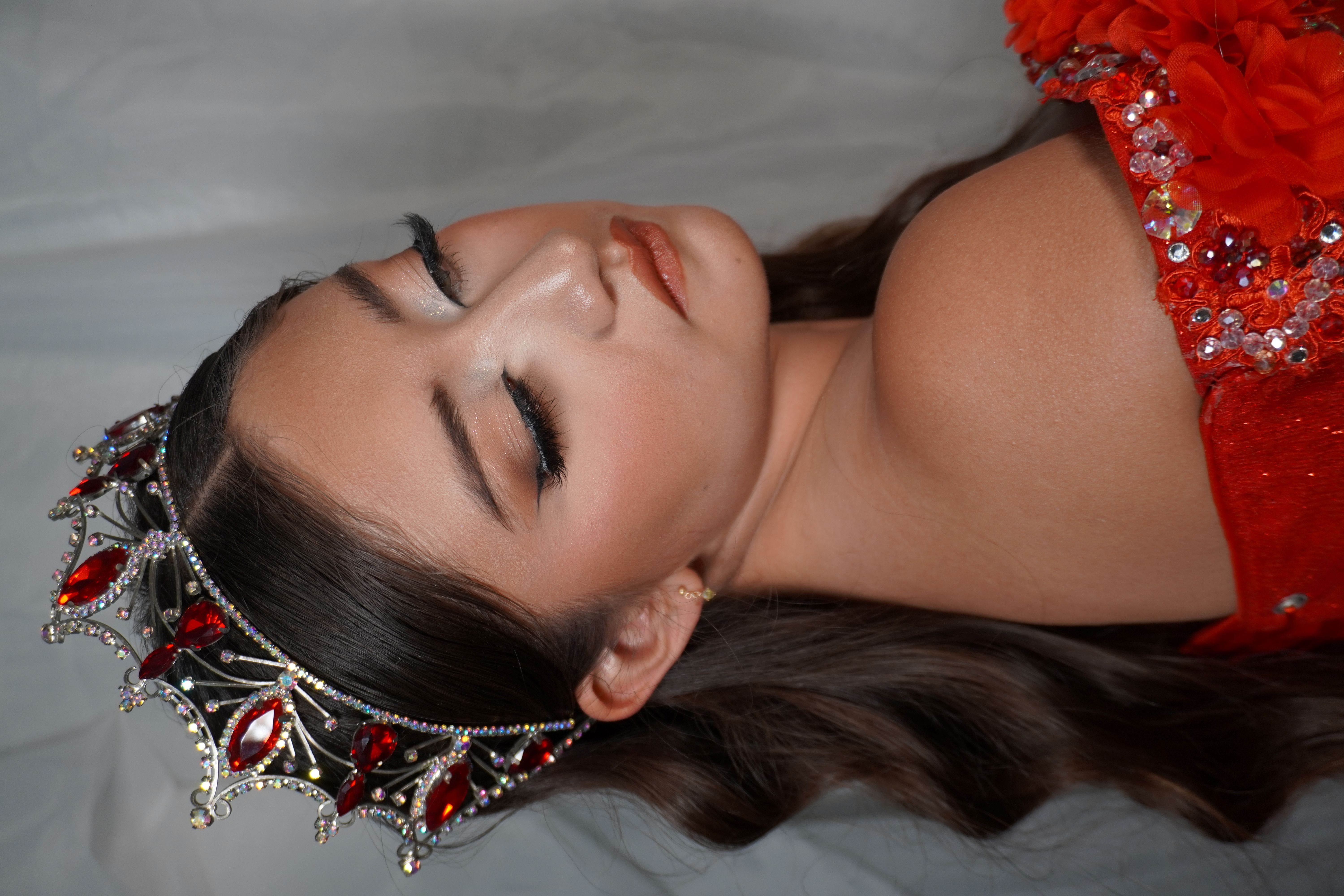 Quinceañera de rojo con glitter plateado en los ojos y ondas suaves
